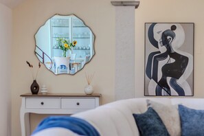 Une chambre à coucher avec un lit, une commode, un miroir qui reflète un coin repas et un tableau accroché au mur.