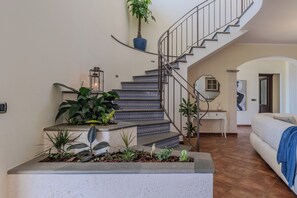 Un escalier avec une rampe, un pot de fleurs et un luminaire fixé au mur.