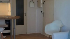 Een kamer met een eettafel, een witte stoel, een bank en een kast.