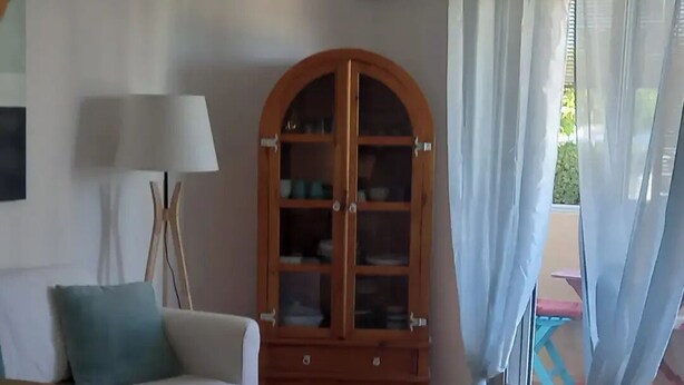 Een woonkamer met een witte bank, een houten kast en drie ronde matten op de vloer.