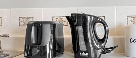 Une cuisine équipée d’un grille-pain, d’une bouilloire et d’une tasse posée sur le comptoir.