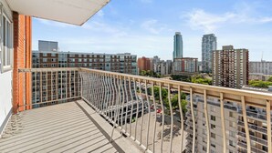 Un balcón con vista a un paisaje urbano, que incluye edificios altos y un estacionamiento.