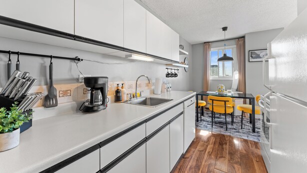 Una cocina moderna con armarios blancos, una cafetera y un comedor con sillas amarillas.