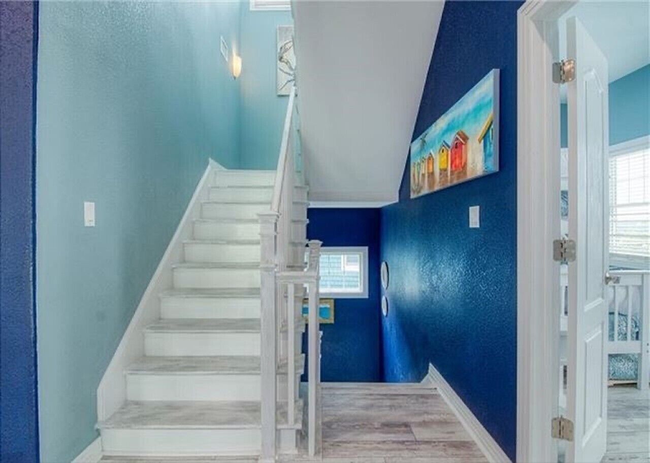 Un escalier menant à un palier avec un mur bleu et un tableau.