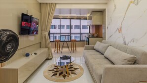 Una sala de estar moderna con un sofá, un televisor, un ventilador y un comedor con taburetes.