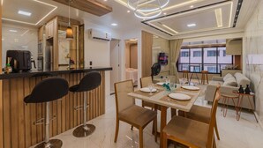 Un moderno comedor con una barra, taburetes de bar, una mesa de comedor preparada para cuatro personas y un sofá al fondo.