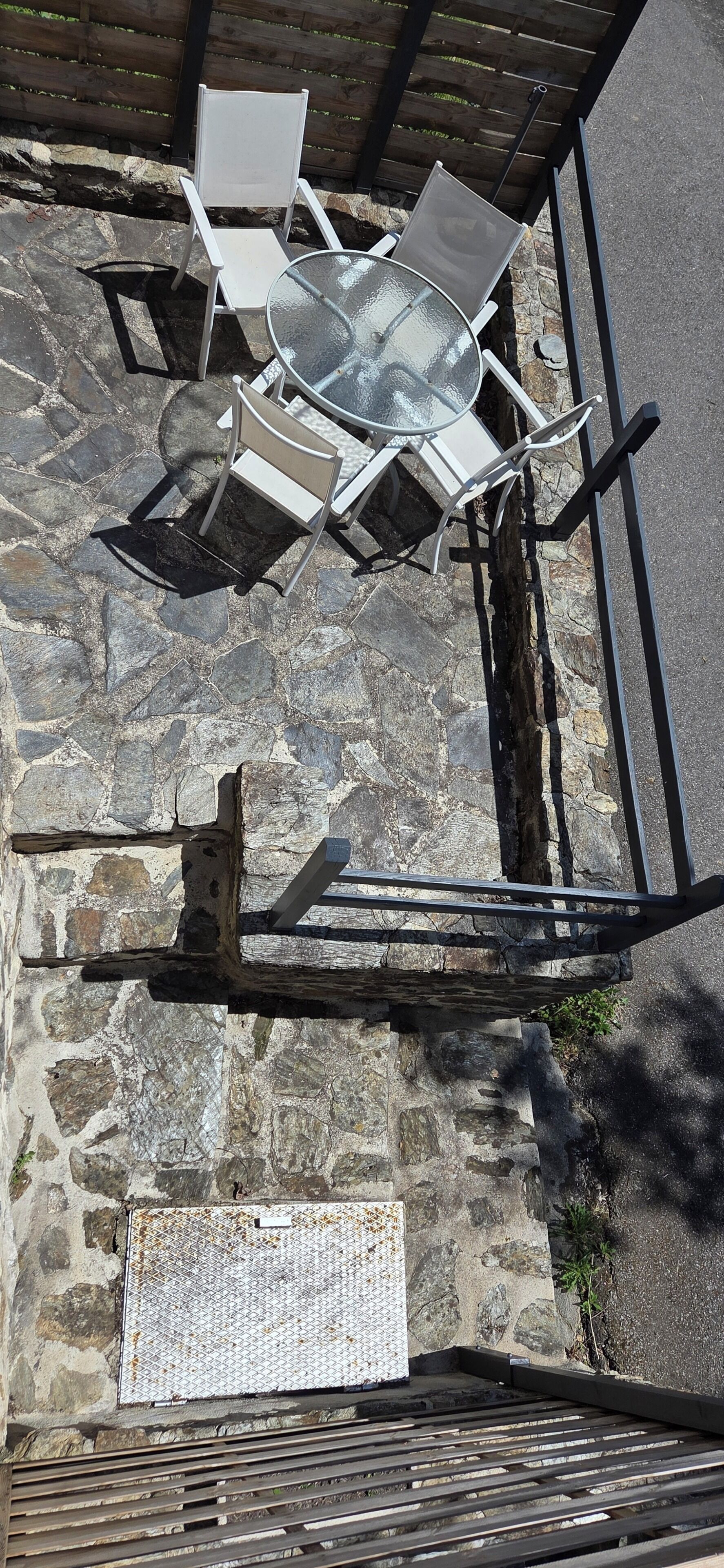 A stone wall with a metal gate, a metal table with chairs, and a wooden bench.