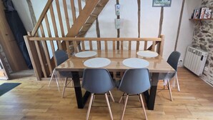 Ein Essbereich mit Holztisch, vier Stühlen, einer Treppe und einer Steinwand.