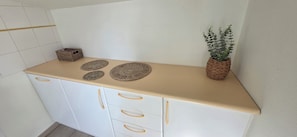 A kitchen with a beige countertop, white cabinets, and a woven basket with a plant.
