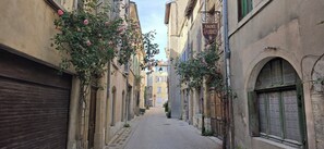 Une rue étroite, bordée de bâtiments des deux côtés, dont certains arborent des enseignes visibles, et un panneau de signalisation indiquant une zone interdite aux véhicules.