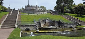 Un bâtiment historique doté d’une tour circulaire, d’une fontaine et d’un escalier menant à son sommet.