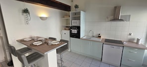 Une cuisine moderne avec un coin repas, des meubles blancs, un four à micro-ondes, un four, un évier et un lave-vaisselle.