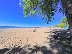 A beach with footprints, a volleyball net, and a building in the background.