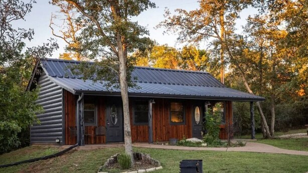 Eine Blockhütte mit Metalldach, Holzfassade und einer kleinen Veranda.