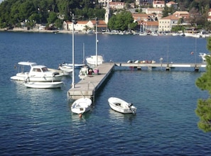 Un puerto deportivo con varias embarcaciones amarradas, un muelle que se adentra en el agua y edificios al fondo.