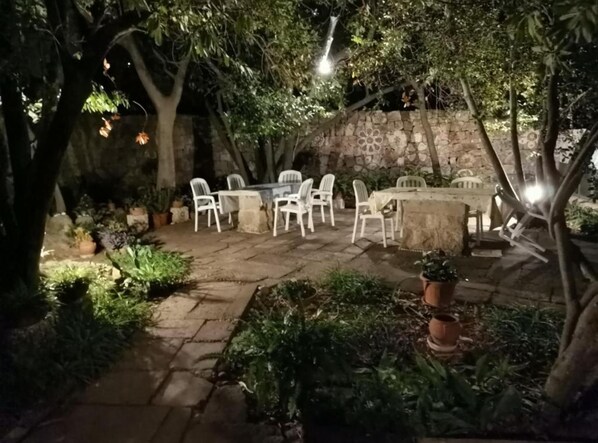 An outdoor patio with stone flooring, white plastic chairs, and a table.
