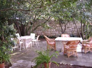 An outdoor patio with stone walls, wicker furniture, and potted plants. - Old Town Bay Cavtat Sea View (Konavle)