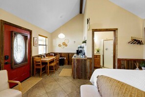 A compact hotel room with a dining area, kitchenette, and a bed.