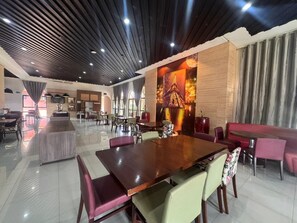 Un comedor amplio con una gran mesa de madera, sillas acolchadas y un diseño de techo moderno.