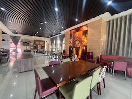 Un comedor amplio con una gran mesa de madera, sillas acolchadas y un diseño de techo moderno.
