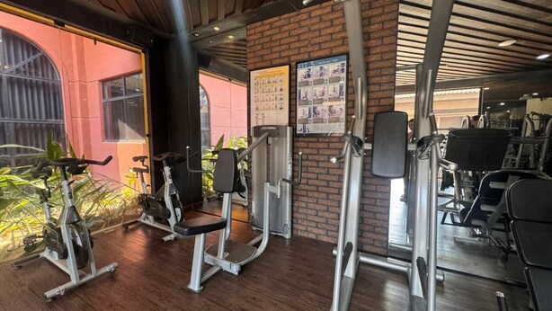 Un gimnasio con equipo de ejercicio, una pared de ladrillo y una ventana con vistas.
