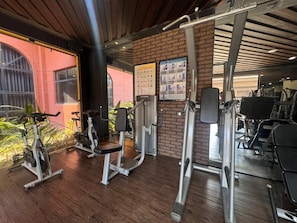 Un gimnasio con equipo de ejercicio, una pared de ladrillo y una ventana con vistas.