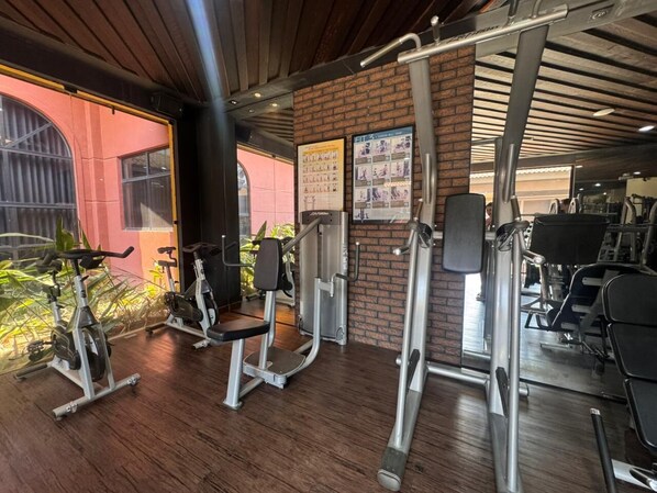 Une salle de sport équipée de matériel d’exercice, avec un mur en briques et une fenêtre donnant sur un paysage agréable.
