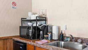 Une cuisine compacte équipée d’un lave-vaisselle, d’un four à micro-ondes, d’une machine à café et d’un évier.