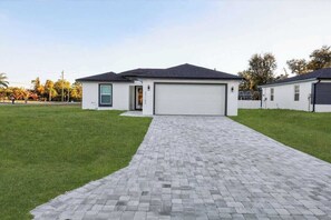 A modern two-story house with a paved driveway leading to a garage. - Charming Home in Port Charlotte – Sunshine Getaway (Port Charlotte)