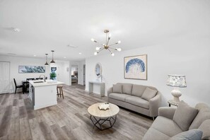 Een moderne woonkamer met een bank, een salontafel en een eethoek met een keukeneiland.