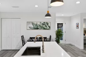 A modern kitchen with a white countertop, a stainless steel faucet, and a pendant light. - Charming Home in Port Charlotte – Sunshine Getaway (Port Charlotte)
