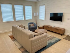 A living room with a sectional sofa, a small round table, a television, and a lamp.