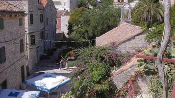 A narrow street with stone buildings, a small bridge, and a tree-lined path.