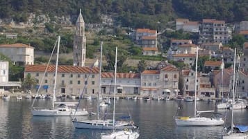 A coastal town with a marina, buildings with red-tiled roofs, and a church tower.