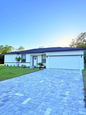A modern single-story house with a garage, a paved driveway, and a well-maintained lawn.