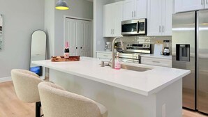 A modern kitchen with a central island, stainless steel appliances, and pendant lighting. - Bright & Spacious 4/2 Home | Near Beaches & Dining (Port Charlotte)