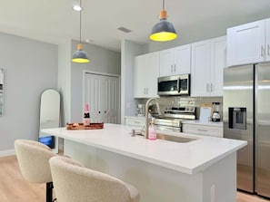 A modern kitchen with a central island, stainless steel appliances, and pendant lighting.