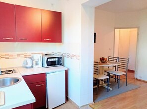 A compact kitchen with red cabinets, a microwave, a coffee maker, and a small refrigerator. - Apartment Amore (Rovinj)