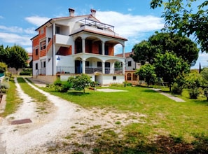 A two-story house with a balcony, a driveway, and a well-maintained lawn. - Apartment Amore (Rovinj)