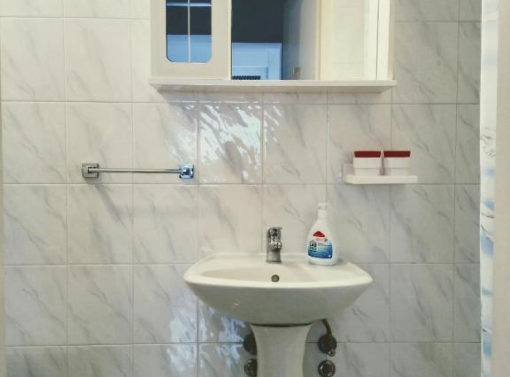 Une salle de bain avec un lavabo blanc, un distributeur de savon liquide et un porte-serviettes.