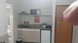 Una cocina compacta con microondas, pileta y heladera pequeña.