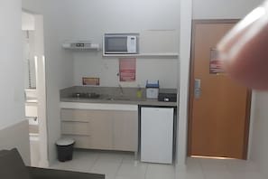 A compact kitchen with a microwave, sink, and a small refrigerator. - HOTEL BOULEVARD SUITES HOTEL  (Caldas Novas)