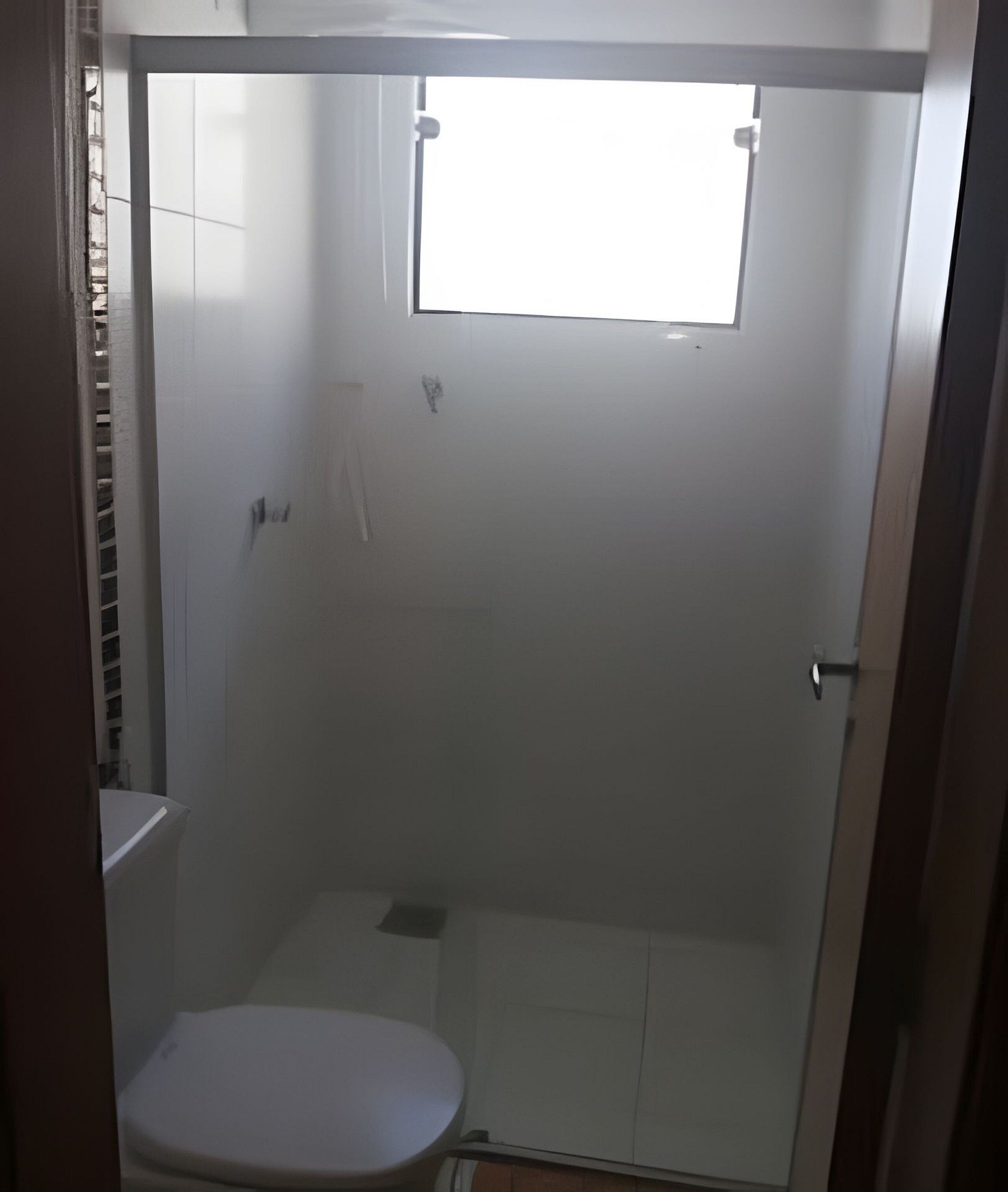 A small, enclosed shower area with a toilet and a window.