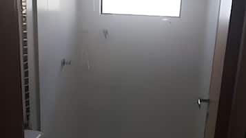 Um chuveiro pequeno e fechado, com um vaso sanitário e uma janela.