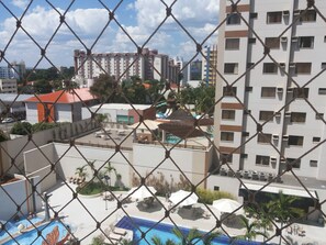 Un hotel con piscina, mobiliario exterior y vistas de edificios circundantes.