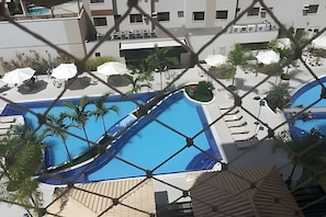 A pool area with multiple swimming pools, lounge chairs, and umbrellas.
