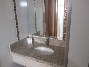 A bathroom with a granite countertop, a white sink, and a mirror. - HOTEL BOULEVARD SUITES HOTEL  (Caldas Novas)