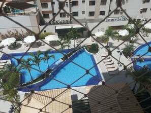 A pool area with multiple swimming pools, sun loungers, and umbrellas. - HOTEL BOULEVARD SUITES HOTEL  (Caldas Novas)