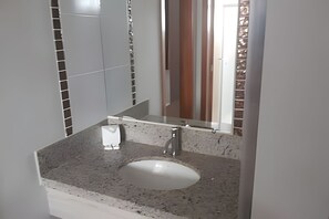 A bathroom with a granite countertop, a white sink, and a mirror. - HOTEL BOULEVARD SUITES HOTEL  (Caldas Novas)