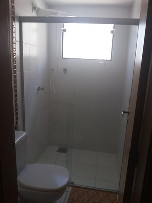 A bathroom with a toilet, a shower enclosure, and a window.